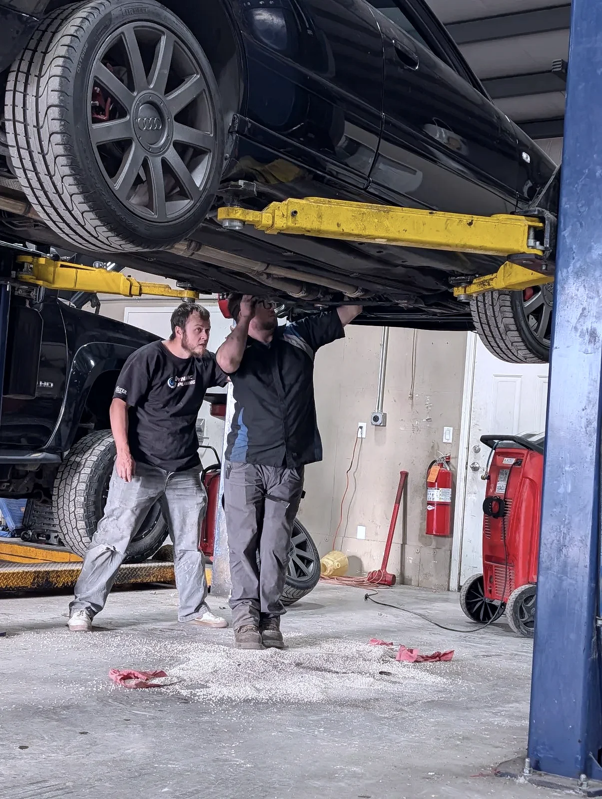 Mechanics in uniform inspecting a truck on the lift at The Automotive Shop in Jerome, Idaho